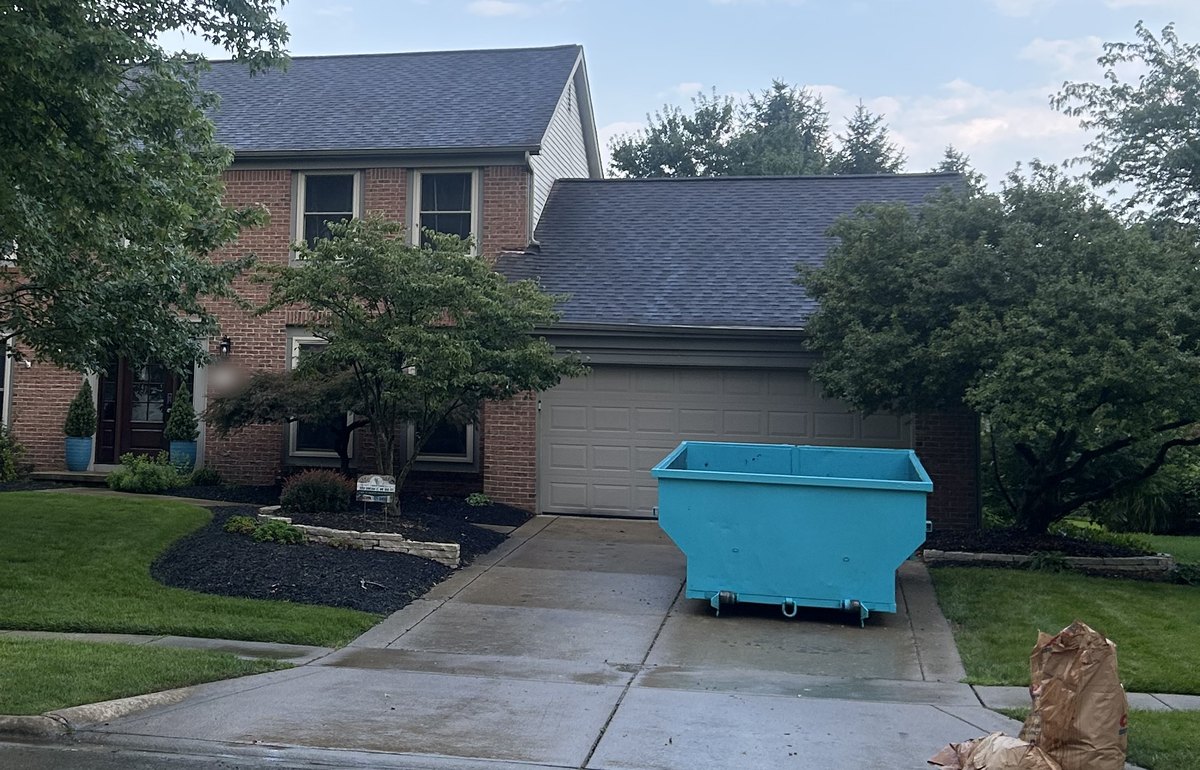 Clean teal roll-off dumpster parked on a residential driveway in Dublin, Ohio